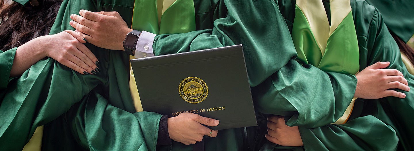 Students wearing graduation robes and holding degree folders