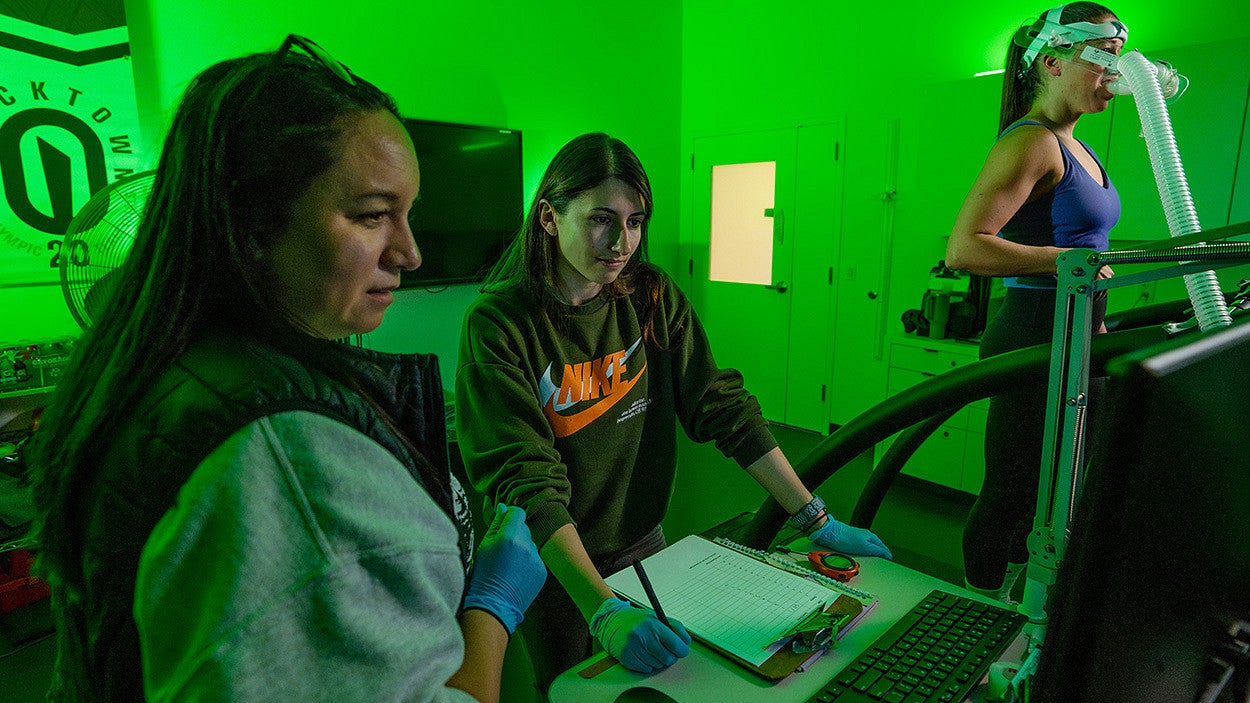 Students and teacher in a lab measuring the performance of a runner on a treadmill.
